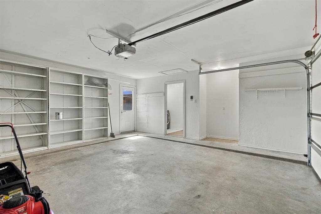 1015 Shelly Drive, Keene, TX 76031 Concrete flooring, extensive built-in shelving, overhead garage door opener, interior access door, additional storage alcove