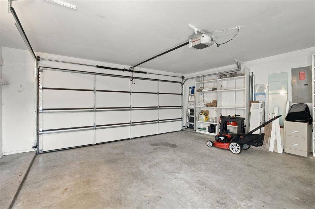 1015 Shelly Drive, Keene, TX 76031 Concrete flooring, white paneled garage door, exposed garage door opener, white painted walls, and built-in shelving