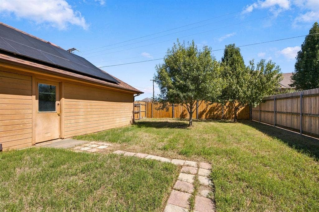 1015 Shelly Drive, Keene, TX 76031 Side yard featuring a stone paver pathway, mature trees, and a wood privacy fence