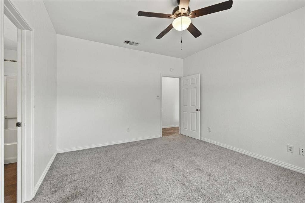 1015 Shelly Drive, Keene, TX 76031 Neutral wall paint, ceiling fan with integrated lighting, gray carpet flooring, white trim, and a paneled interior door