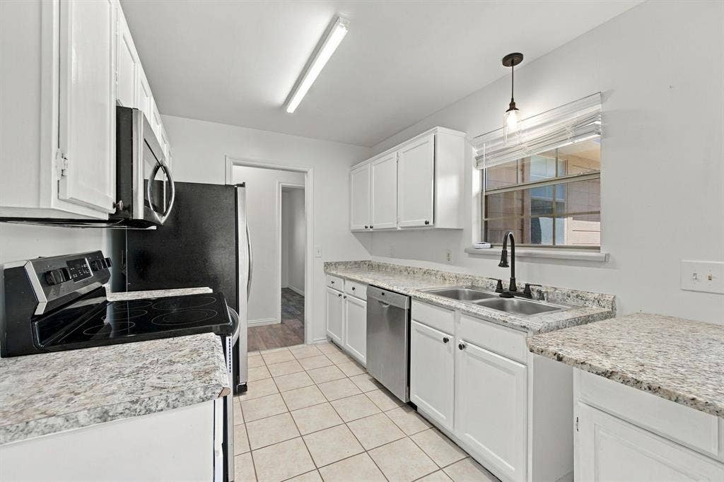 1015 Shelly Drive, Keene, TX 76031 Kitchen featuring white cabinetry, granite-look countertops, stainless steel sink, black range, and tile flooring