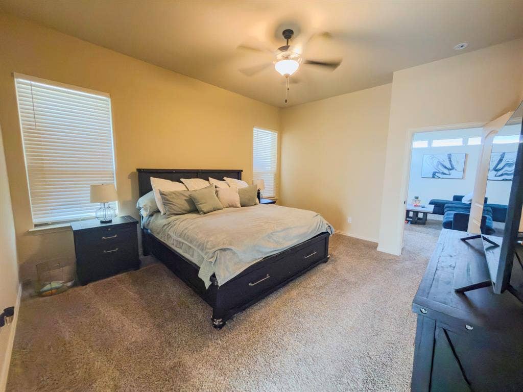 Plush carpeting, vaulted ceiling, and an overhead ceiling fan with lighting