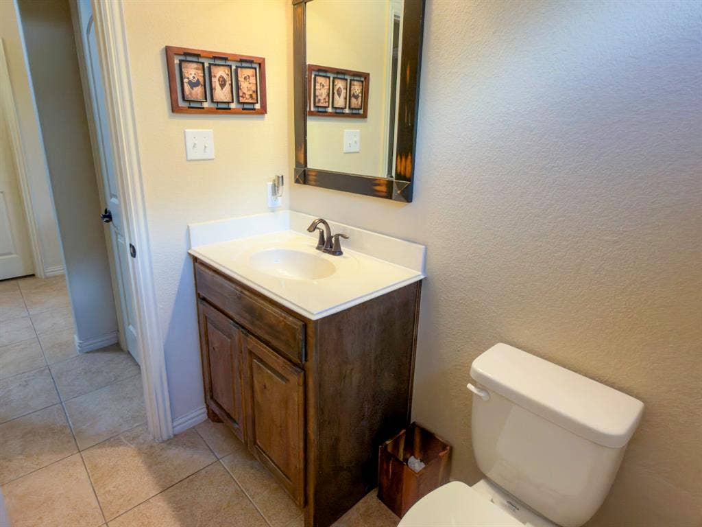 Wood-finish vanity with an integrated sink, bronze-finish faucet, and coordinating framed mirror