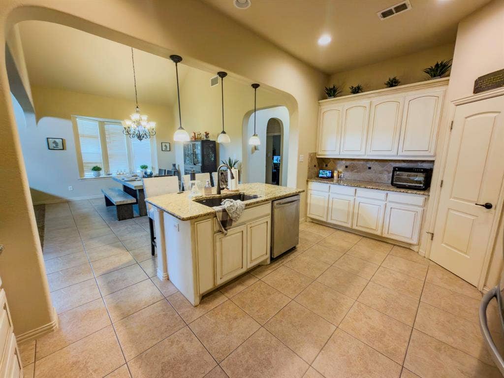 Kitchen featuring a central island with sink, pendant lighting, and granite countertops