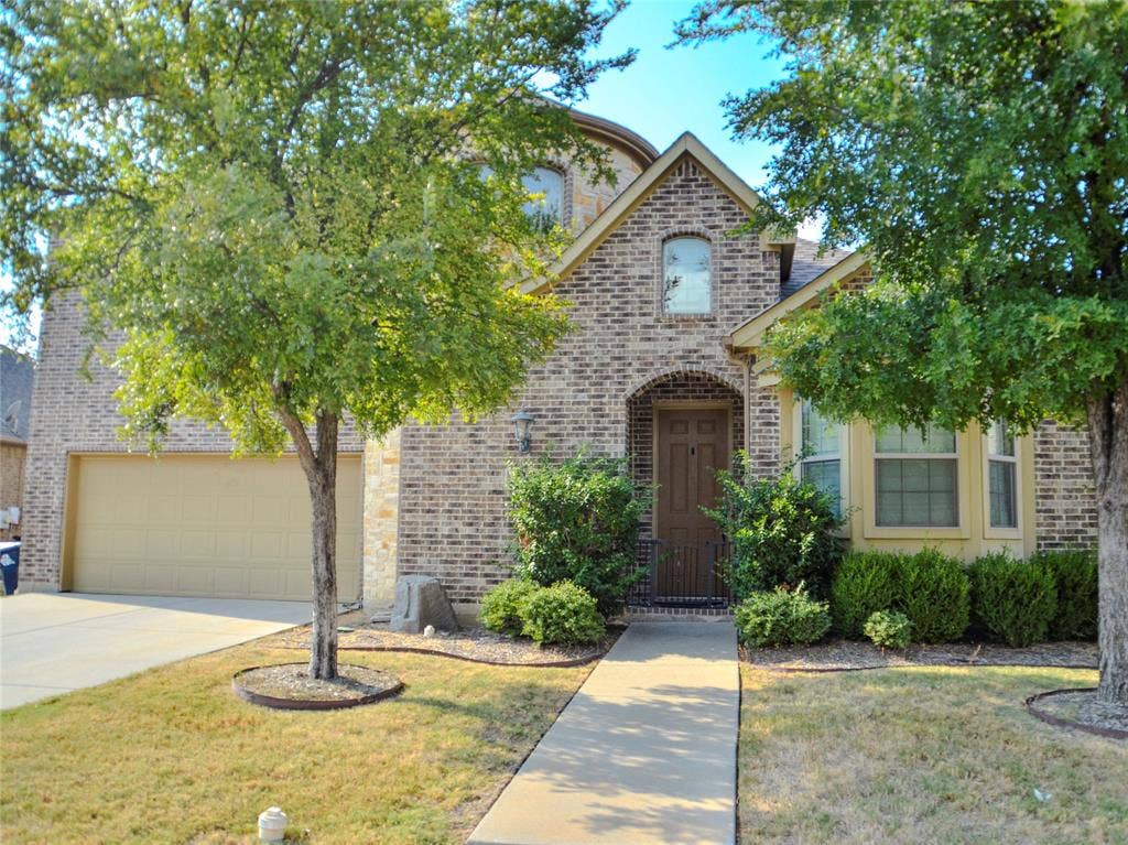 Brick exterior facade with stone accents, arched entryway, bay window, and attached garage