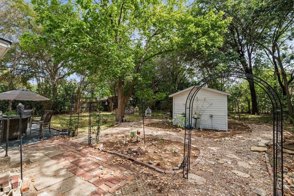 302 W Billington Drive, Robinson, TX 76706 Expansive outdoor space featuring a brick patio, mature trees, a storage shed, and decorative metal archways