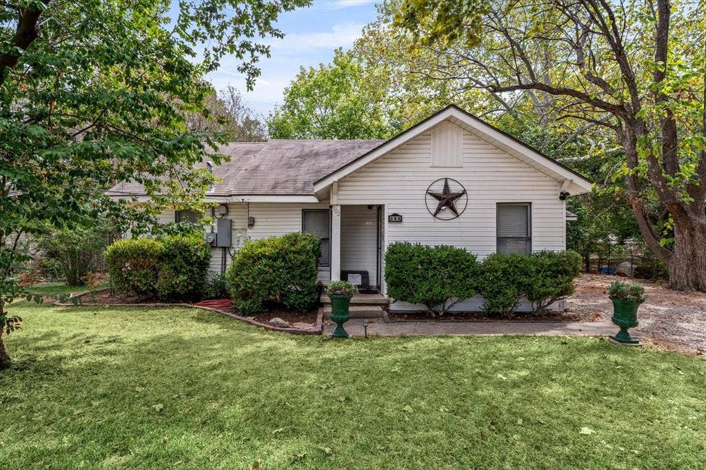302 W Billington Drive, Robinson, TX 76706 White siding exterior, gabled roofline, mature trees, landscaped shrubbery, and a manicured lawn