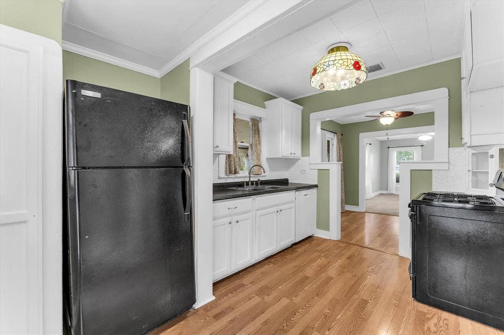 302 W Billington Drive, Robinson, TX 76706 Kitchen featuring wood-finish flooring, white cabinetry, a black refrigerator, a black range, and a decorative ceiling light fixture