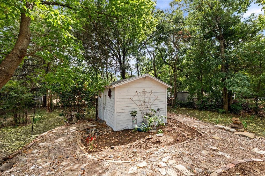 302 W Billington Drive, Robinson, TX 76706 Backyard storage shed with white horizontal siding and a gable roof, surrounded by mature trees and a stone pathway