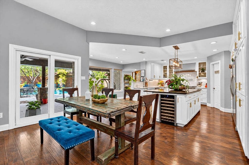7016 Battle Creek Road, Fort Worth, TX 76116 Hardwood flooring throughout, with a spacious kitchen island featuring a built-in wine refrigerator, white cabinetry with gold-finish hardware, and recessed lighting