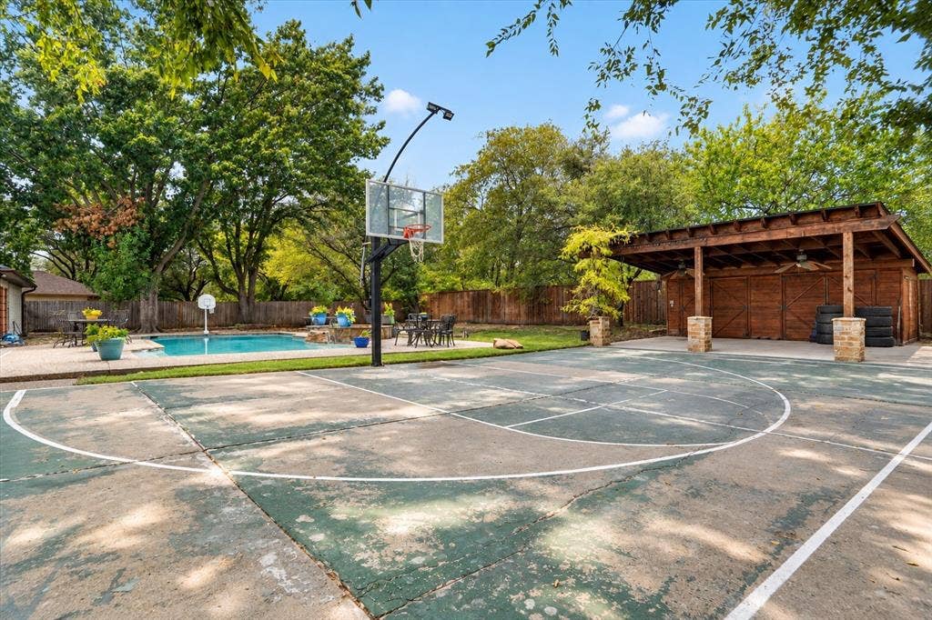 7016 Battle Creek Road, Fort Worth, TX 76116 Outdoor sport court, built-in swimming pool, wooden pergola with ceiling fans, brick fencing, and mature trees