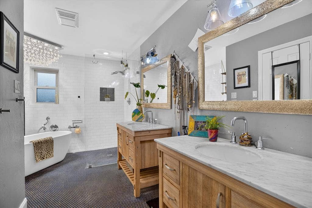 7016 Battle Creek Road, Fort Worth, TX 76116 Dual wood-finish vanities with stone countertops, a freestanding soaking tub, and a separate glass-enclosed shower featuring white subway tile