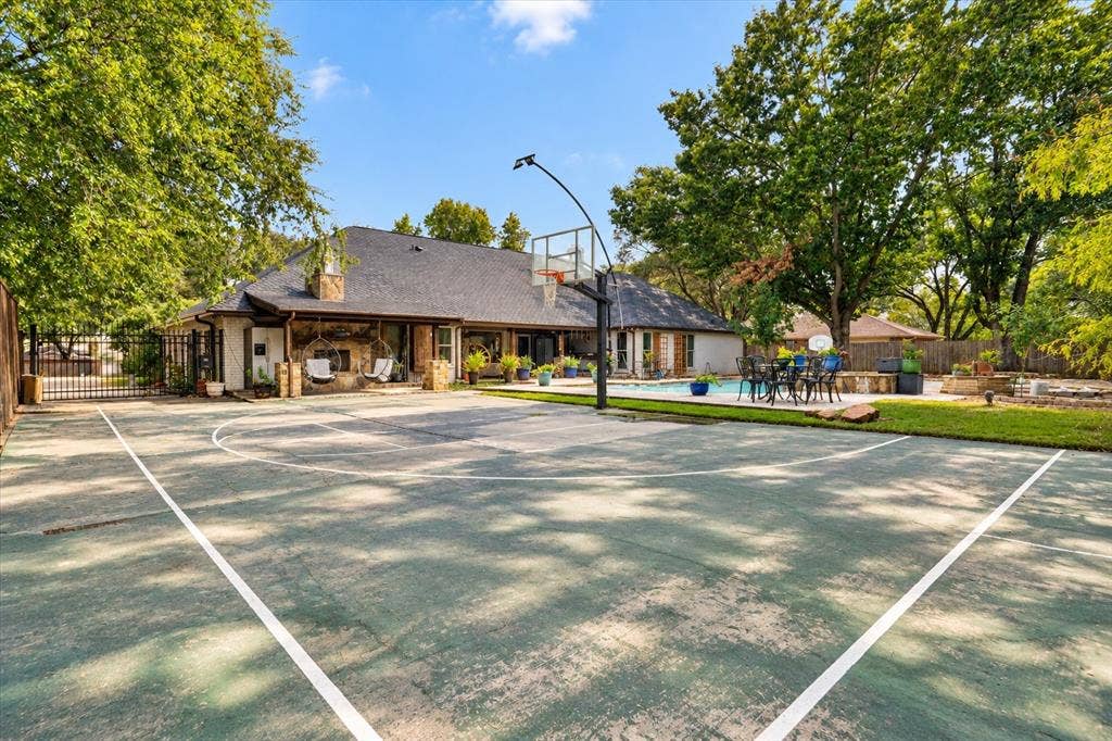 7016 Battle Creek Road, Fort Worth, TX 76116 Expansive sport court with a permanent basketball hoop, a swimming pool, and a stone-clad exterior with a covered patio
