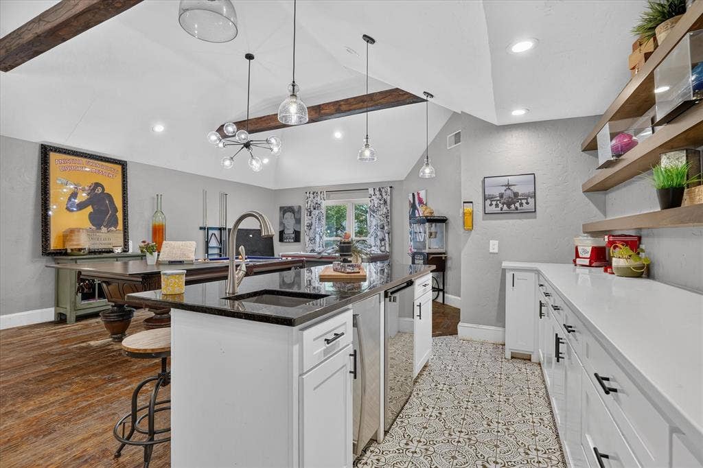 7016 Battle Creek Road, Fort Worth, TX 76116 Spacious room featuring exposed ceiling beams, recessed lighting, an island with a built-in sink and dark countertop, white cabinetry with black hardware, and wood-finish flooring