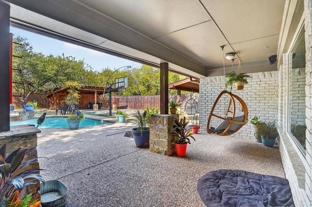 7016 Battle Creek Road, Fort Worth, TX 76116 Covered patio with an exposed aggregate concrete surface, white brick exterior, and stone accents