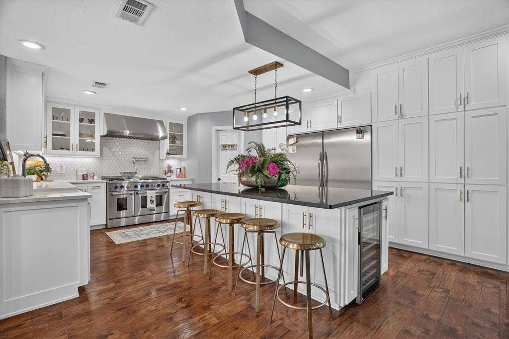 7016 Battle Creek Road, Fort Worth, TX 76116 Gourmet kitchen with wood-finish flooring, white cabinetry, a large kitchen island with a dark countertop, and professional-grade stainless steel appliances