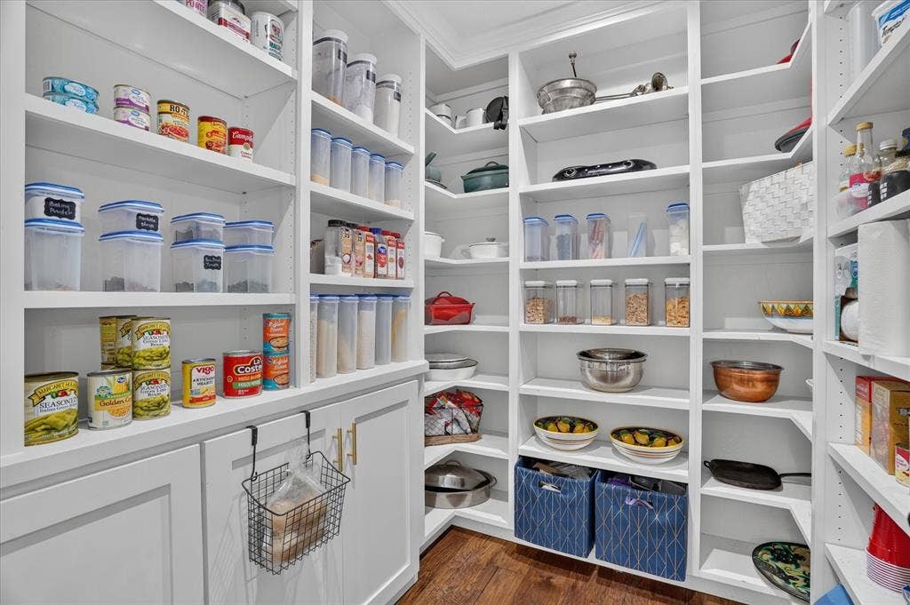 7016 Battle Creek Road, Fort Worth, TX 76116 Expansive pantry with built-in white shelving, wood-finish flooring, and lower white cabinetry with gold-tone hardware