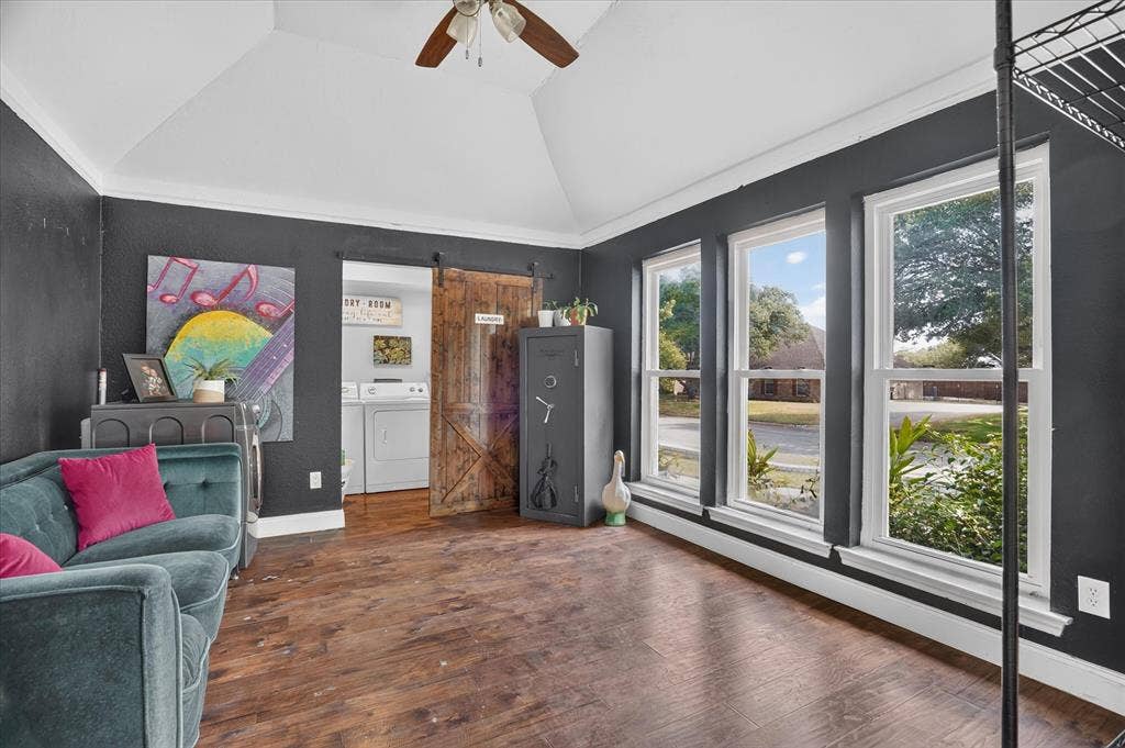 7016 Battle Creek Road, Fort Worth, TX 76116 Vaulted ceiling with a ceiling fan, three large windows, wood-finish flooring, and a sliding barn door