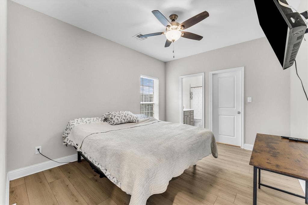 Recessed window with blinds, wood-finish flooring, ceiling fan with light fixture, and white interior doors