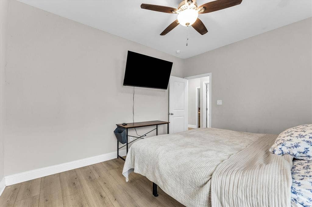 Wood-finish flooring with light gray walls, white trim, and a ceiling fan with integrated lighting