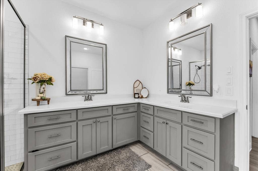 Dual vanity with light gray cabinetry, white countertops, and framed mirrors