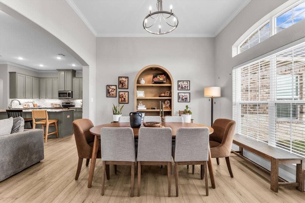 Open-concept living space featuring wood-finish flooring, a contemporary chandelier, and a kitchen with gray cabinetry and stainless steel appliances