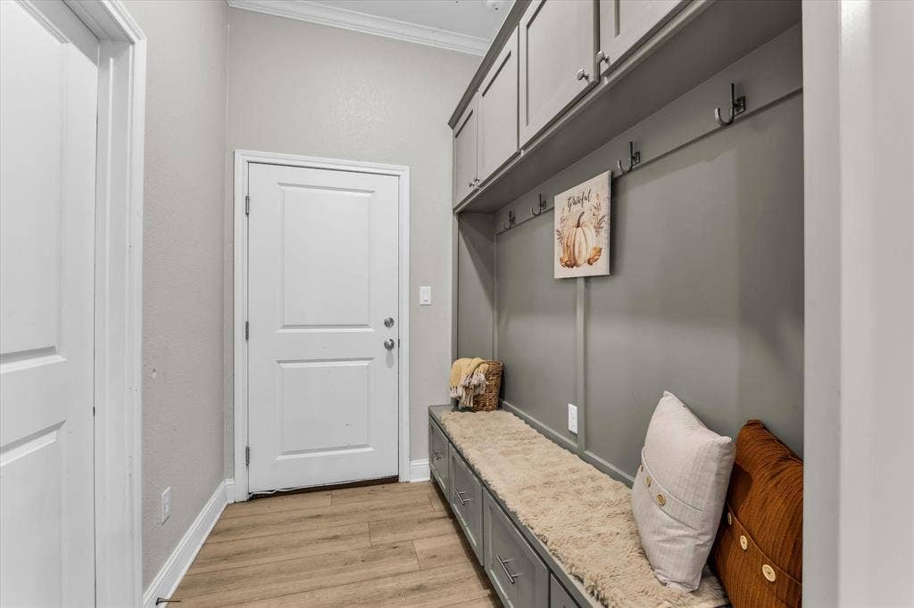 Dedicated mudroom featuring custom built-in cabinetry with granite countertop, overhead storage shelving, and wood-finish flooring