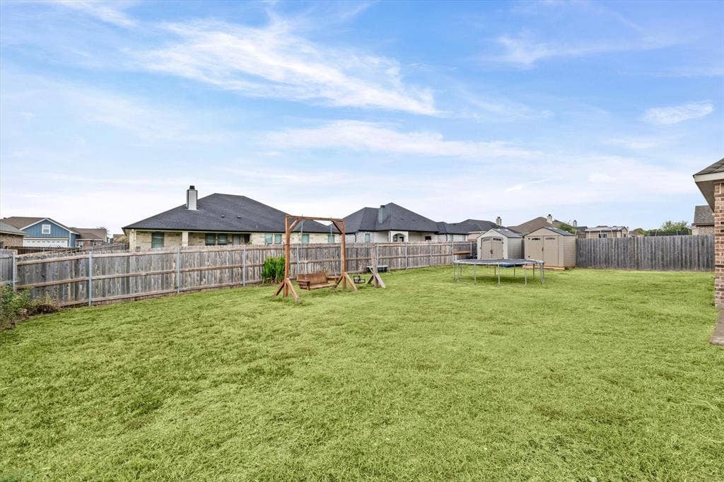 Expansive grass lawn with wood privacy fencing and two storage sheds