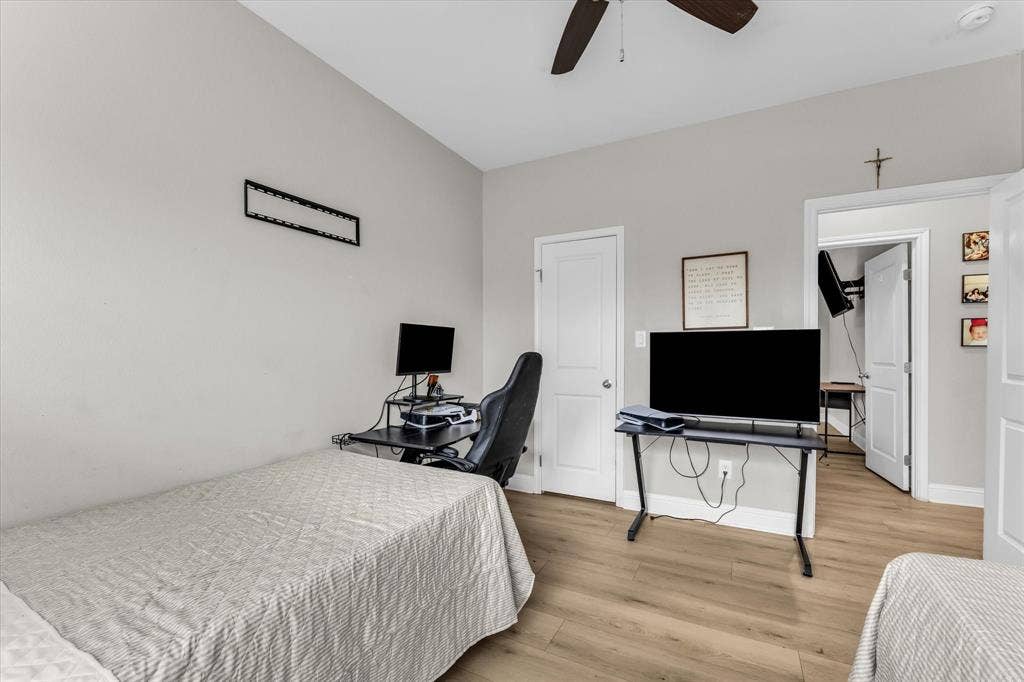 Light gray wall paint, wood-finish flooring, two white doors, and a ceiling fan