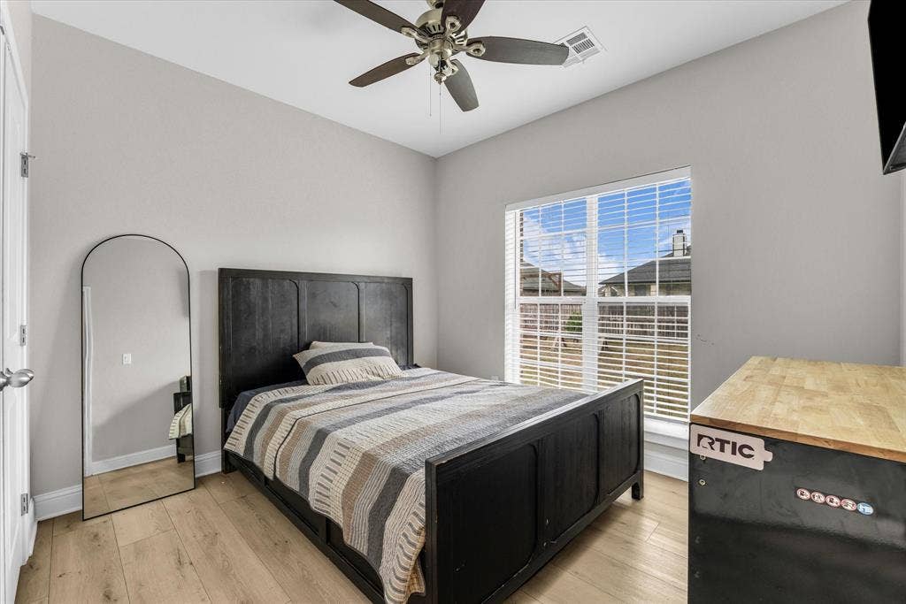 Vaulted ceiling with a ceiling fan, wood-finish flooring, and a window with blinds