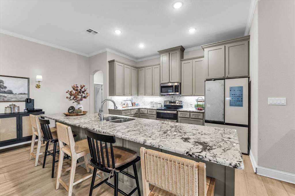 Gourmet kitchen featuring custom cabinetry, quartz countertops, stainless steel appliances, and a spacious island with seating