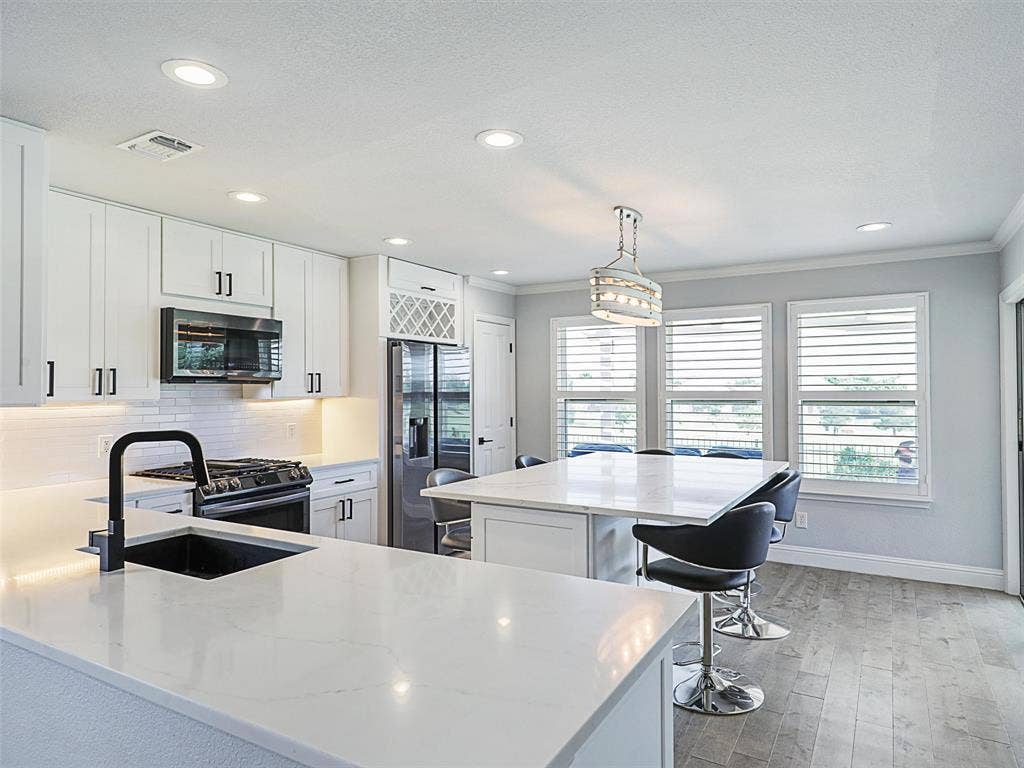 7470 Birmingham Forest Drive, Frisco, TX 75036 Kitchen with a kitchen island, hanging light fixtures, tasteful backsplash, black appliances. Adjustable Bar Height Stools are included!