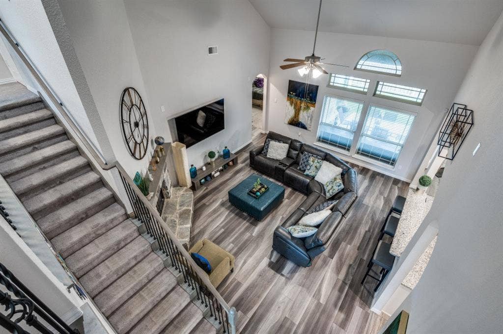 249 Noble Nest Drive, Midlothian, TX 76065 Two-story living area featuring vaulted ceilings, wood-finish flooring, a stone-faced fireplace