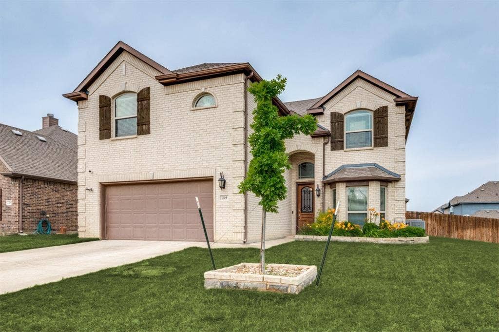249 Noble Nest Drive, Midlothian, TX 76065 Two-story brick facade, arched entryway, bay window with decorative shutters, integrated two-car garage, and a concrete driveway