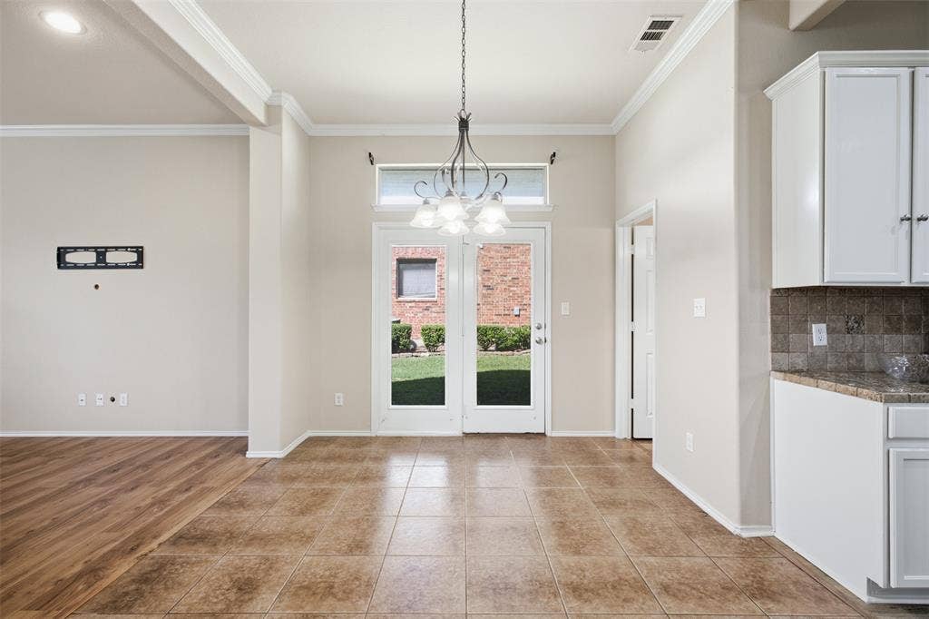 750 Village Green Drive, DeSoto, TX 75115 Glass-paneled door with transom window, tile flooring, wood-finish flooring, white cabinetry, and a built-in chandelier