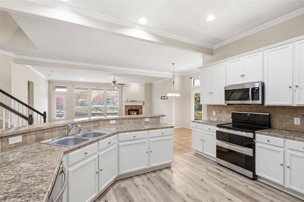 750 Village Green Drive, DeSoto, TX 75115 Kitchen featuring white cabinetry, stainless steel appliances, a double basin sink, and wood-finish flooring