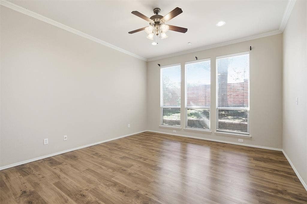 750 Village Green Drive, DeSoto, TX 75115 Wood-finish flooring, crown molding, three large windows with blinds, ceiling fan with integrated lighting, and recessed lighting