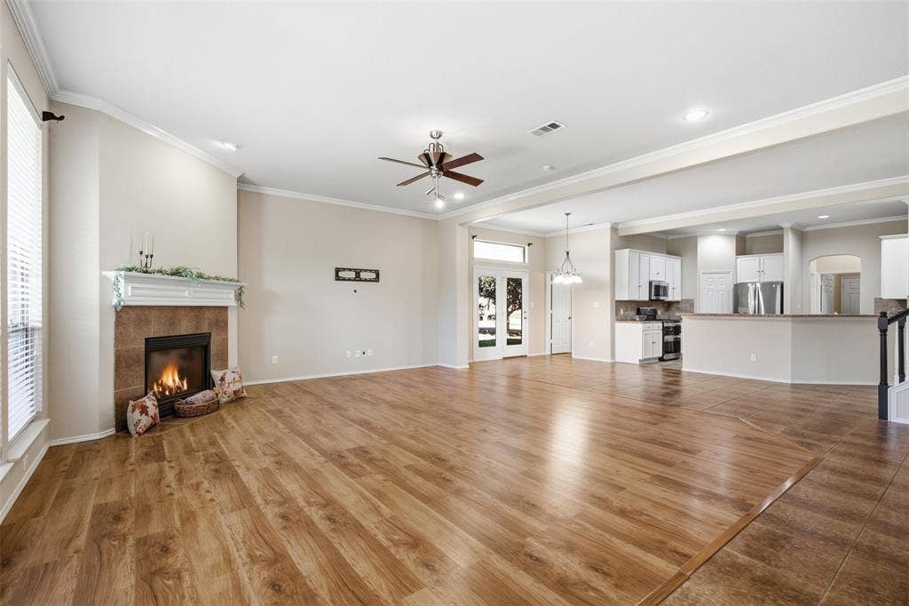 750 Village Green Drive, DeSoto, TX 75115 Spacious interior featuring wood-finish flooring, a tile-surround fireplace with a white mantel, and an open-concept layout