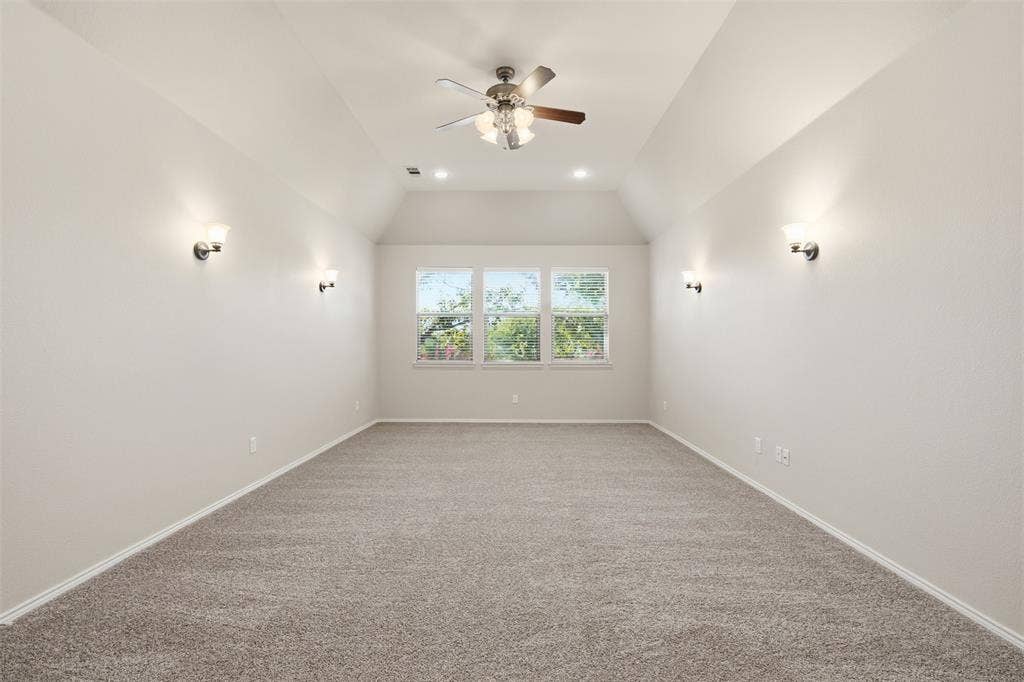 750 Village Green Drive, DeSoto, TX 75115 Vaulted ceiling with a ceiling fan, recessed lighting, wall sconces, triple windows, and carpet flooring