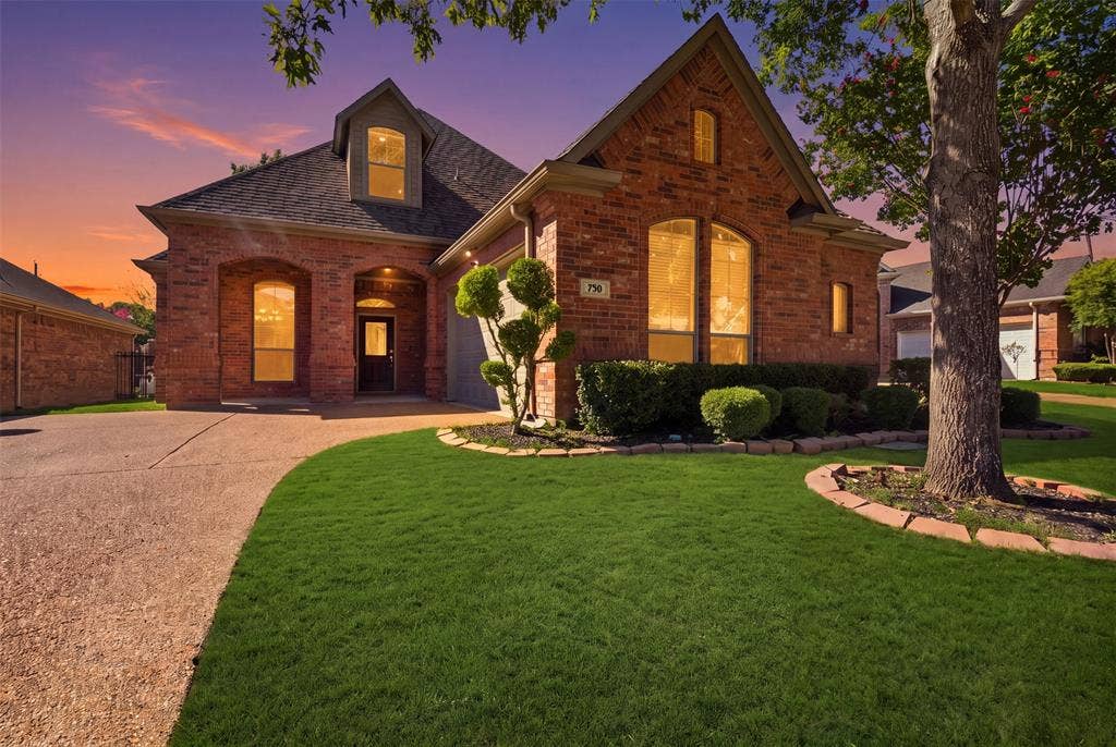 750 Village Green Drive, DeSoto, TX 75115 Brick exterior with arched entryways, gabled roofline, dormer window, and mature landscaping. Green enhancement to lawn.