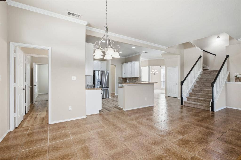 750 Village Green Drive, DeSoto, TX 75115 Expansive tiled flooring extending into an open-concept kitchen with white cabinetry and stainless steel appliances