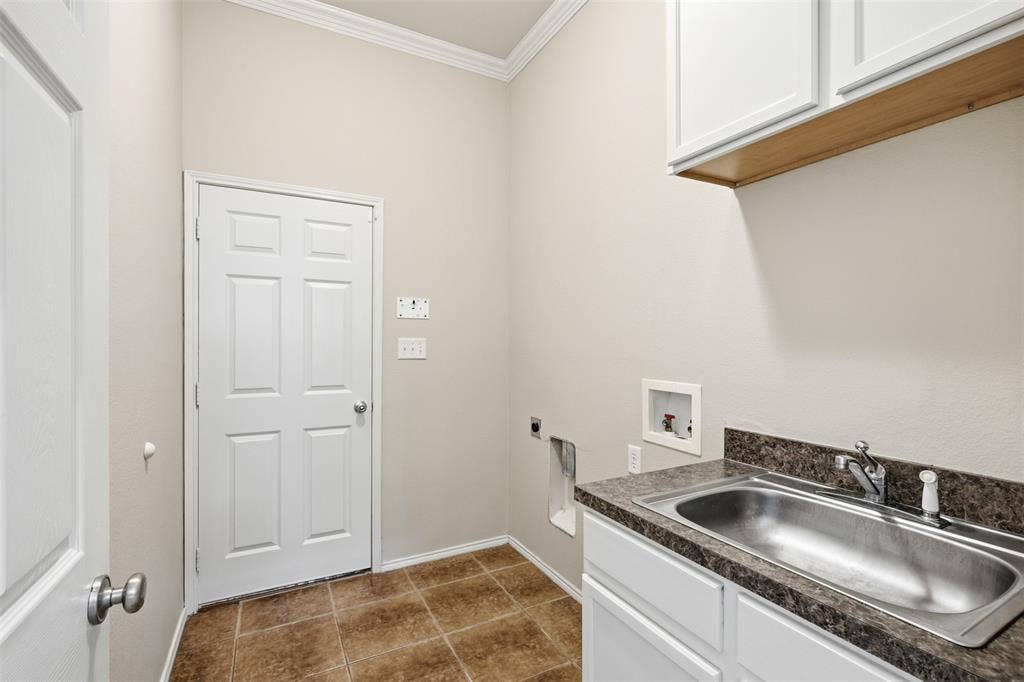 750 Village Green Drive, DeSoto, TX 75115 Laundry area featuring a utility sink, white cabinetry, and tiled flooring