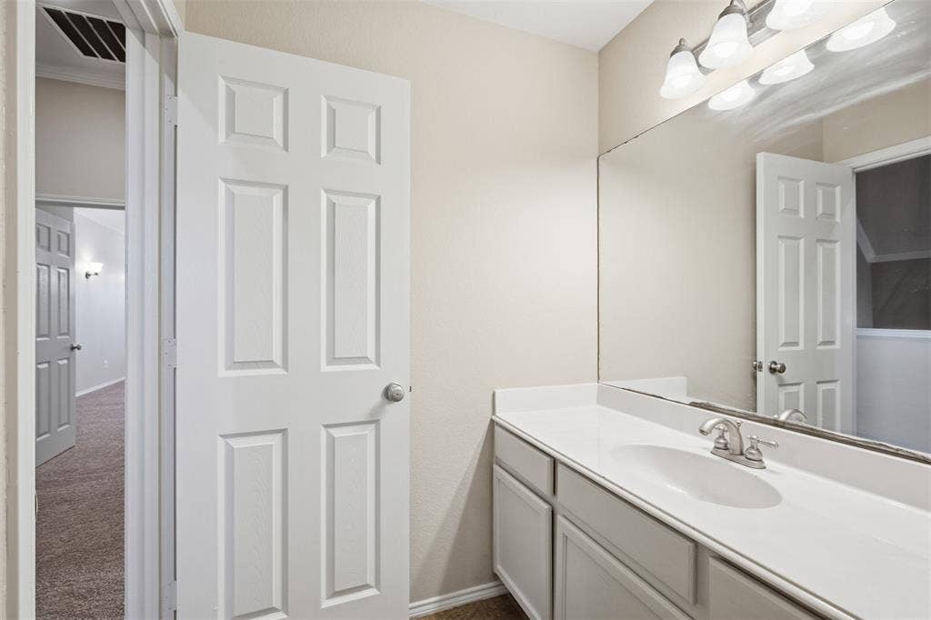 750 Village Green Drive, DeSoto, TX 75115 Vanity with integrated sink, brushed nickel faucet, full-width mirror, and a three-light fixture