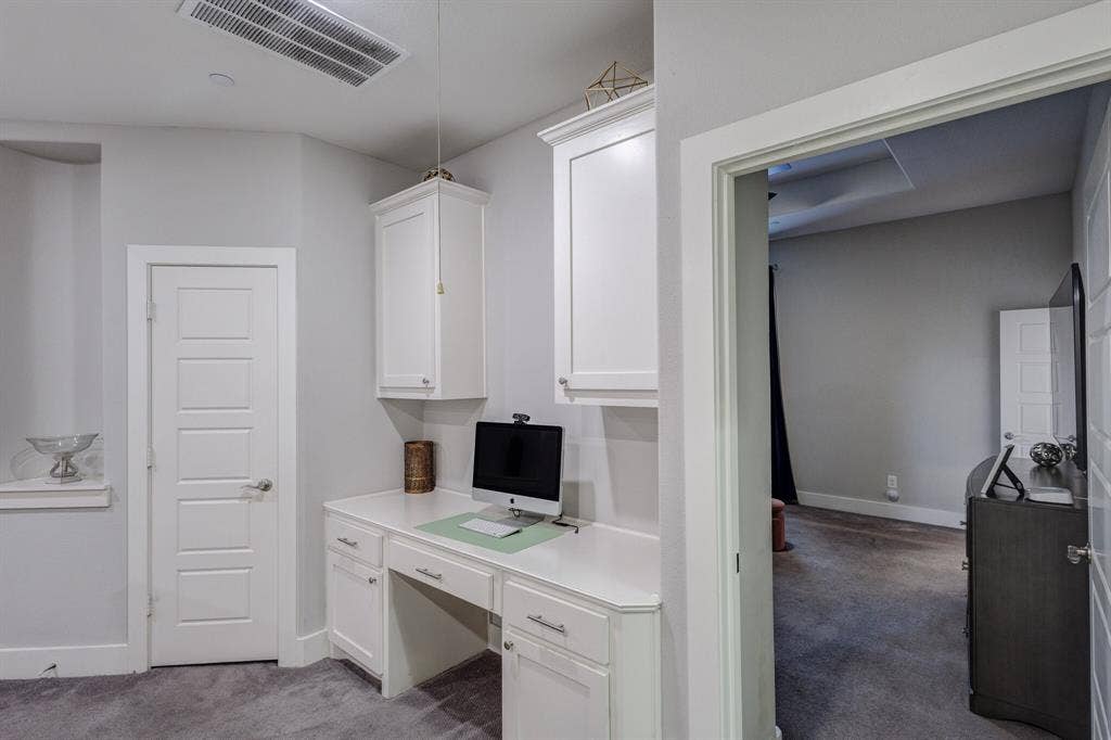 4814 Empire Way, Irving, TX 75038 Built-in desk with white cabinetry and chrome hardware, white paneled doors, and grey carpeting