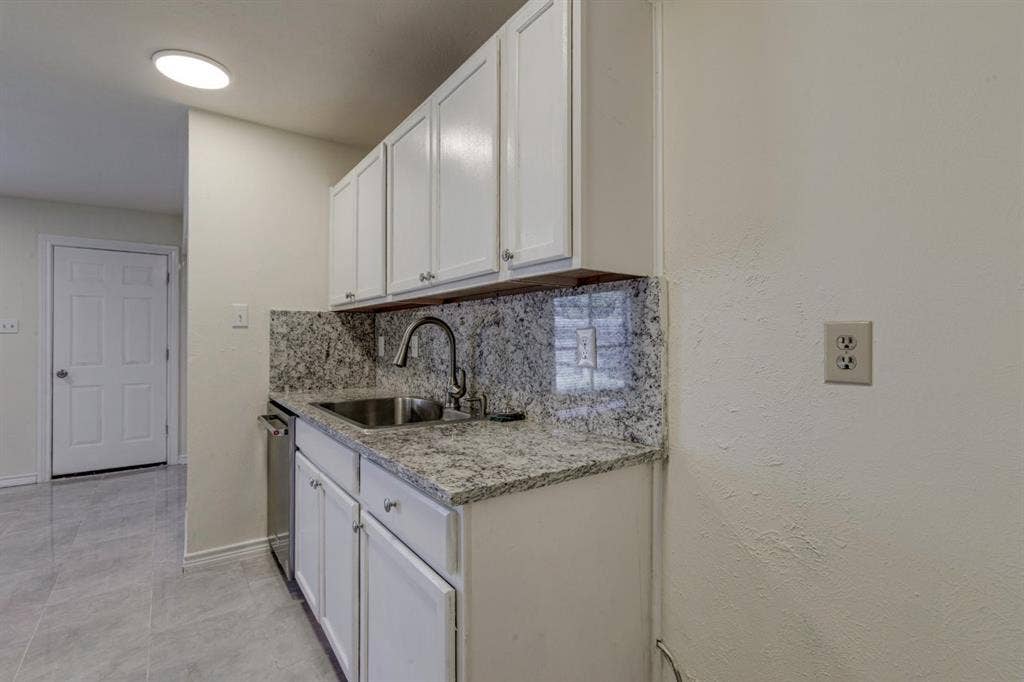 White cabinetry featuring Granite countertops, stainless steel sink with high-arc faucet, and tiled flooring