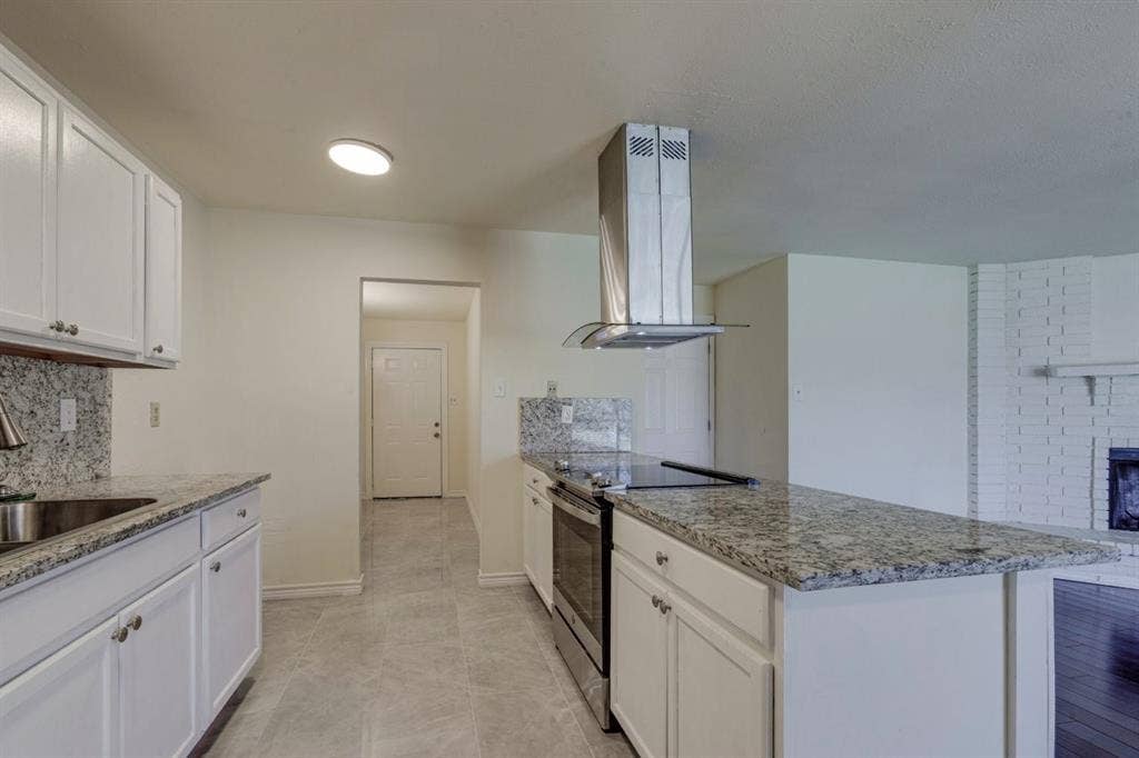Kitchen featuring white cabinetry, Granite countertops, stainless steel range with a glass-and-steel vent hood, and tile flooring