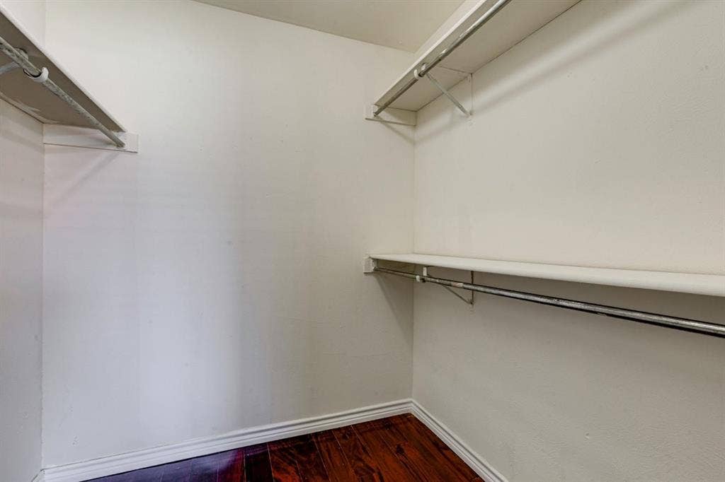 Walk-in closet featuring wood-finish flooring, multi-level shelving, and mounted garment rods