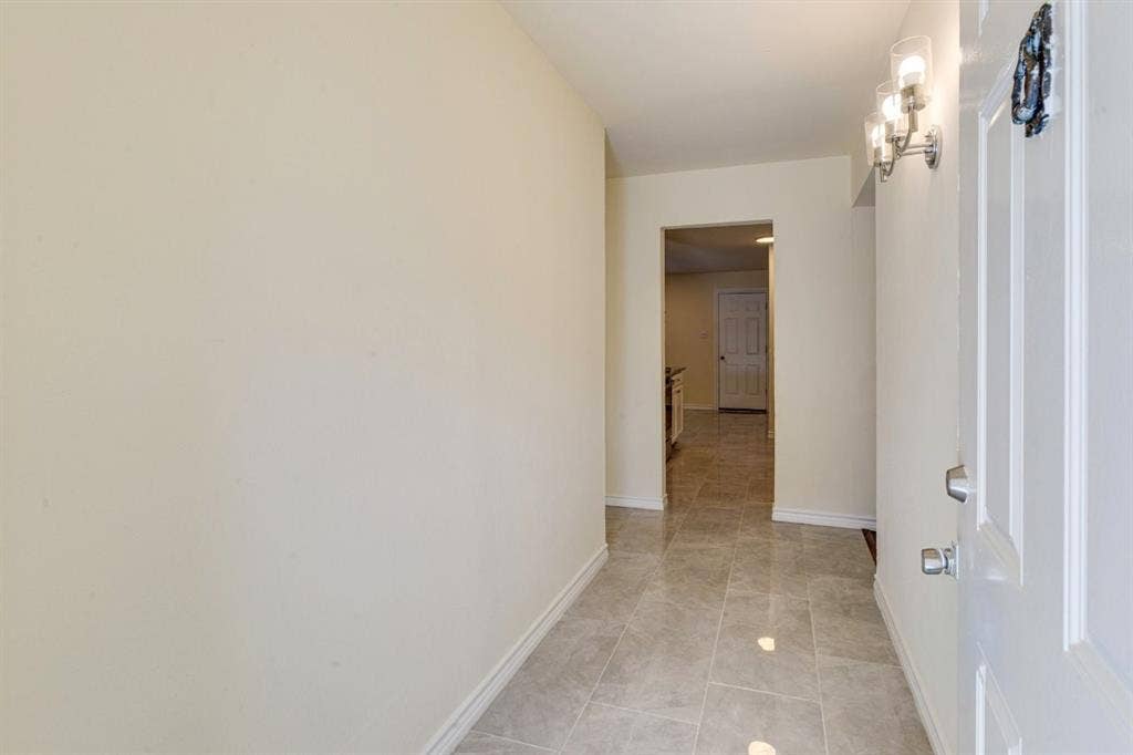 Entryway featuring large-format ceramic tile flooring, neutral wall tones, and a wall-mounted multi-bulb light fixture