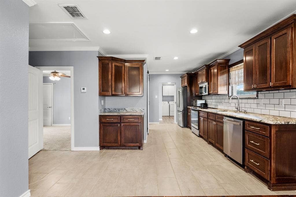 605 Dallas Street, Winona, TX 75792 Kitchen featuring wood cabinetry, stone countertops, stainless steel appliances, subway tile backsplash, and tile flooring