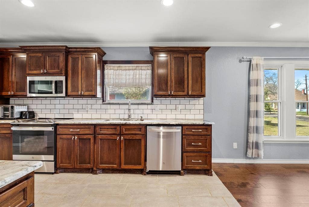 605 Dallas Street, Winona, TX 75792 Kitchen featuring wood cabinetry, stainless steel appliances, white subway tile backsplash, and light-toned countertops